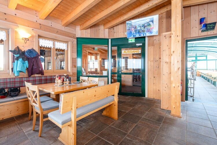 Gemütlicher Gastraum mit Holzwänden, Polsterbänken und Holztischen, warm beleuchtet. | © Mitterhausalm | Alpine Genusswelten