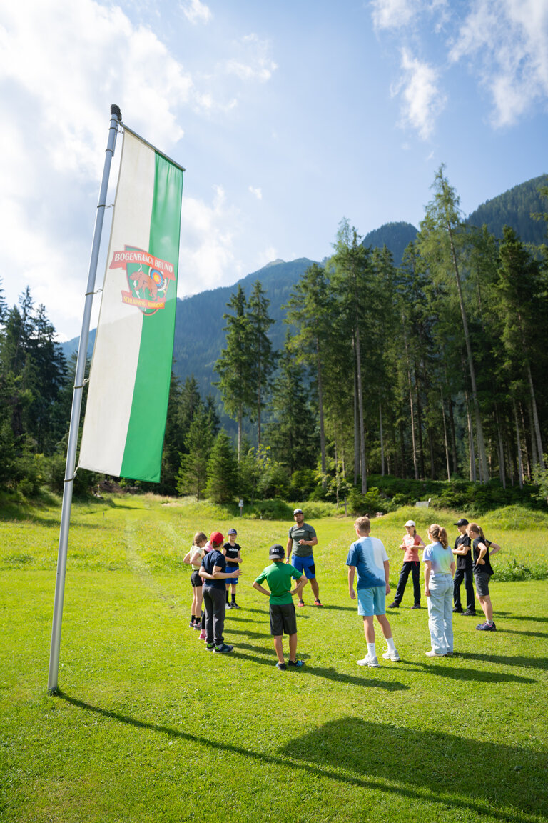 Kindergruppe auf Wiese beim Aufwärmen auf der Bogenranch Bruno in den Bergen. | © TVB/Laura Passenbrunner