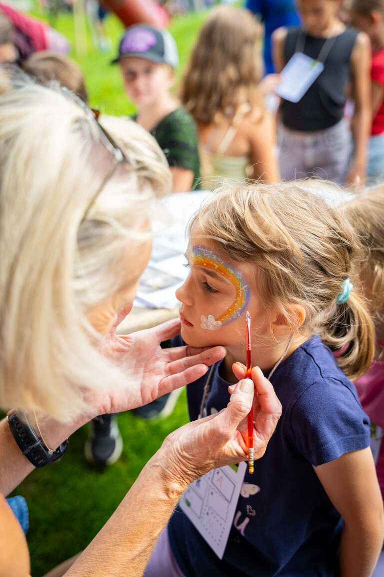 Kind bekommt beim Kinderprogramm ein buntes Regenbogenmotiv ins Gesicht geschminkt. | © TVB/Laura Passenbrunner