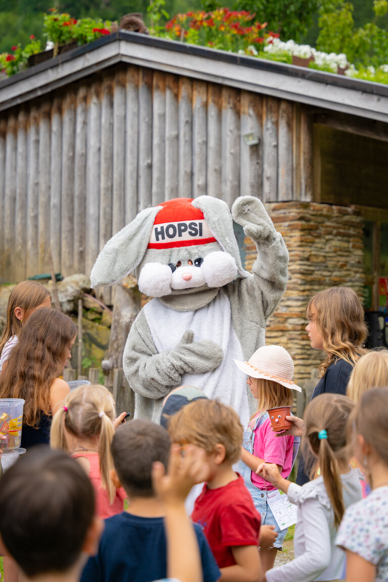 Maskottchen „Hopsi“ begrüßt fröhliche Kindergruppe bei der Veranstaltung Kinderfest | © TVB/Laura Passenbrunner