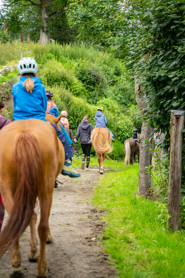 Kinder reiten mit Begleitung auf einem Weg durch grüne Natur. | © TVB/Laura Passenbrunner