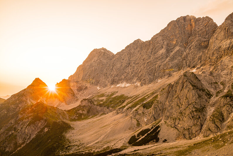 Zwischen Röttelstein und dem Dachstein-Dreigestirn geht die Sonne.  | © Marlene Eggmayr