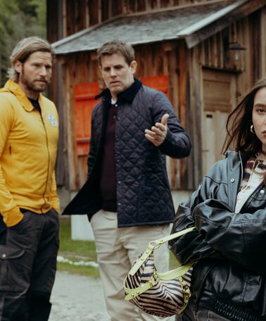 Zwei Männer unterhalten sich über einen Teenager, der genervt an einem Auto lehnt.  | © ZDF_2024_17. Staffel