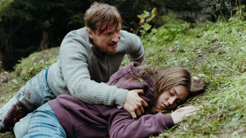 Eine Person liegt bewusstlos im Gras. Ein Mann versucht ihr zu helfen.  | © ZDF_2024_17. Staffel