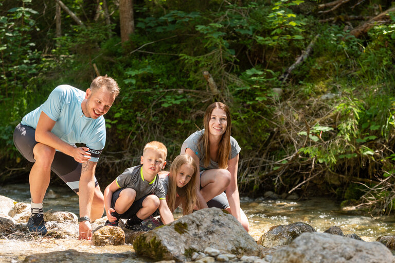 Eine 4-köpfige Familie spielend am Gradenbach  | © Lorenz Maser