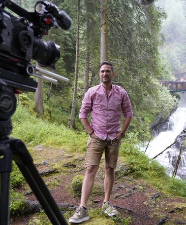 Moderator Richard Deutinger vor der Kamera, Anmoderation am Riesachfall, aufgenommen | © ServusTV / Brigitte Erhart / Degn Film