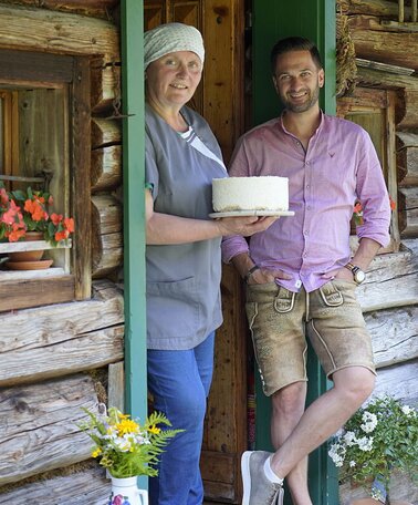 Sennerin Martina Ebenschweiger und Moderator Richard Deutinger posieren für ein Foto auf der Zauneralm | © ServusTV / Brigitte Erhart / Degn Film