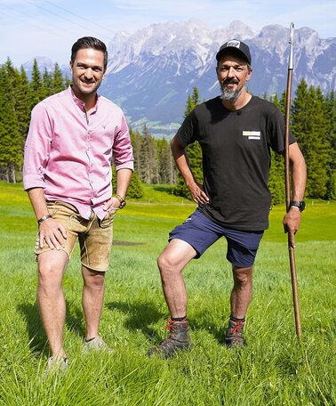 Richard Deutinger und Schäfer Johannes Flatz (rechts) posieren für ein Foto am Hauser Kaibling, im Hintergrund Dachstein-Massiv | © ServusTV / Brigitte Erhart / Degn Film